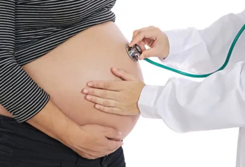 Un médico examina el abdomen de una mujer embarazada.