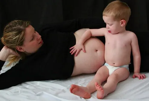 Una madre embarazada deja que su hijo toque su vientre.
